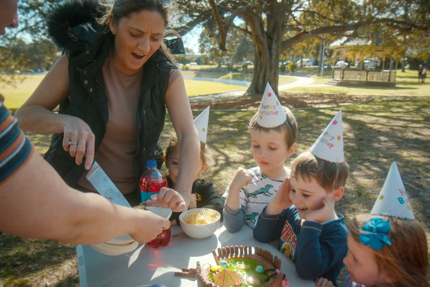 Children at party with birthday cake on table.