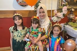 A Uyghur woman sits behind her three children, with balloons in the children's hands. 