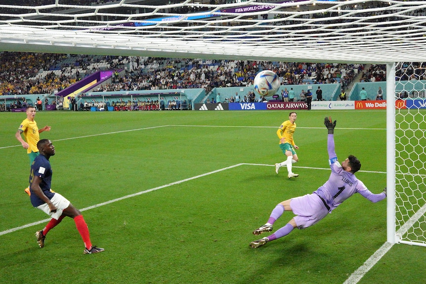 Socceroo Craig Goodwin regarde son tir en diagonale passer devant le gardien plongeant et dans le coin supérieur du filet.