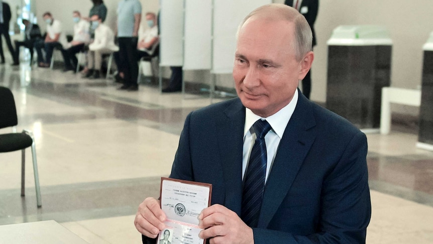 Vladimir Putin, wearing a dark suit and tie shows his passport