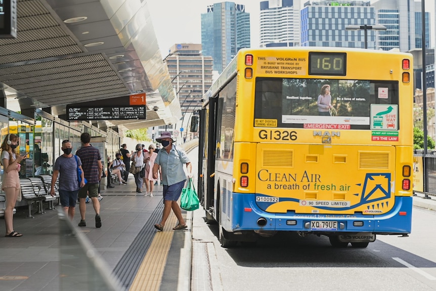 A masked man leaves a bus in Brisbane