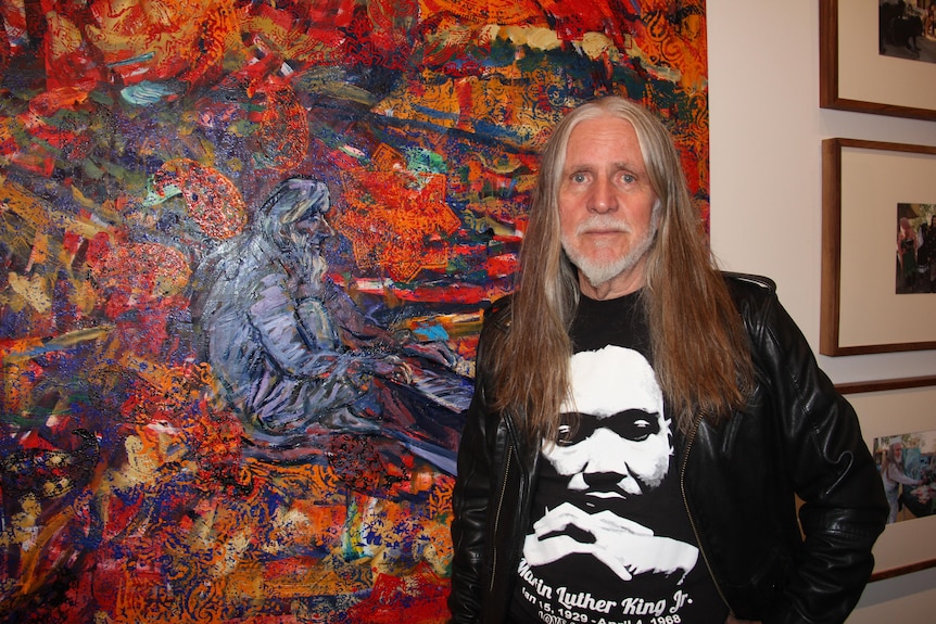 Artist George Gittoes with his painting “Bringing Heaven down to Earth”.