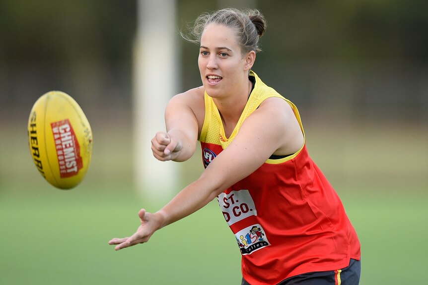 An AFLW player extends her fist after handballing away during an AFLW training session.  