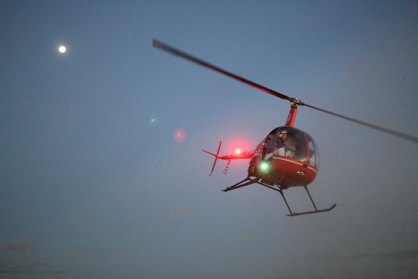a helicopter taking off with a full moon in the background