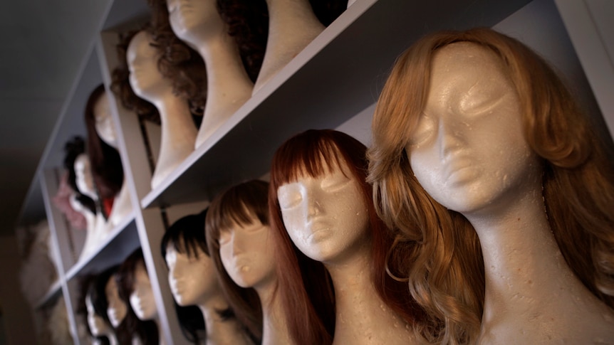Shelves full of mannequin heads wearing wigs of various styles in the ABC's props room.