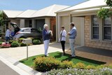 A promotional photograph shows a group of older people chatting in front of a home.