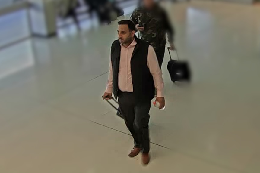 A CCTV image highlighting a man standing in an airport terminal.