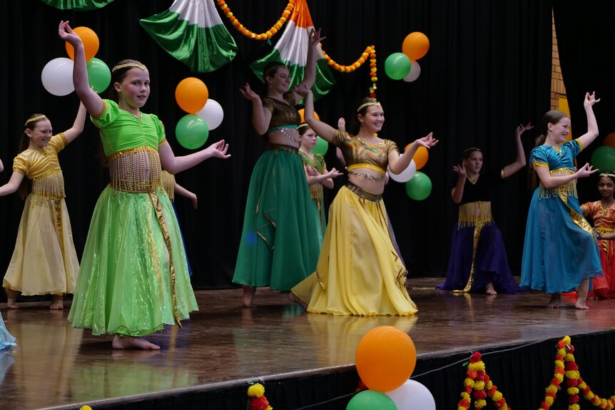 Girls in colourful dresses mid dance on stage