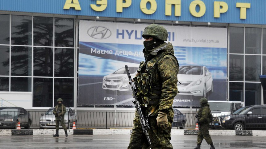 Unidentified armed men patrol outside of Simferopol airport.