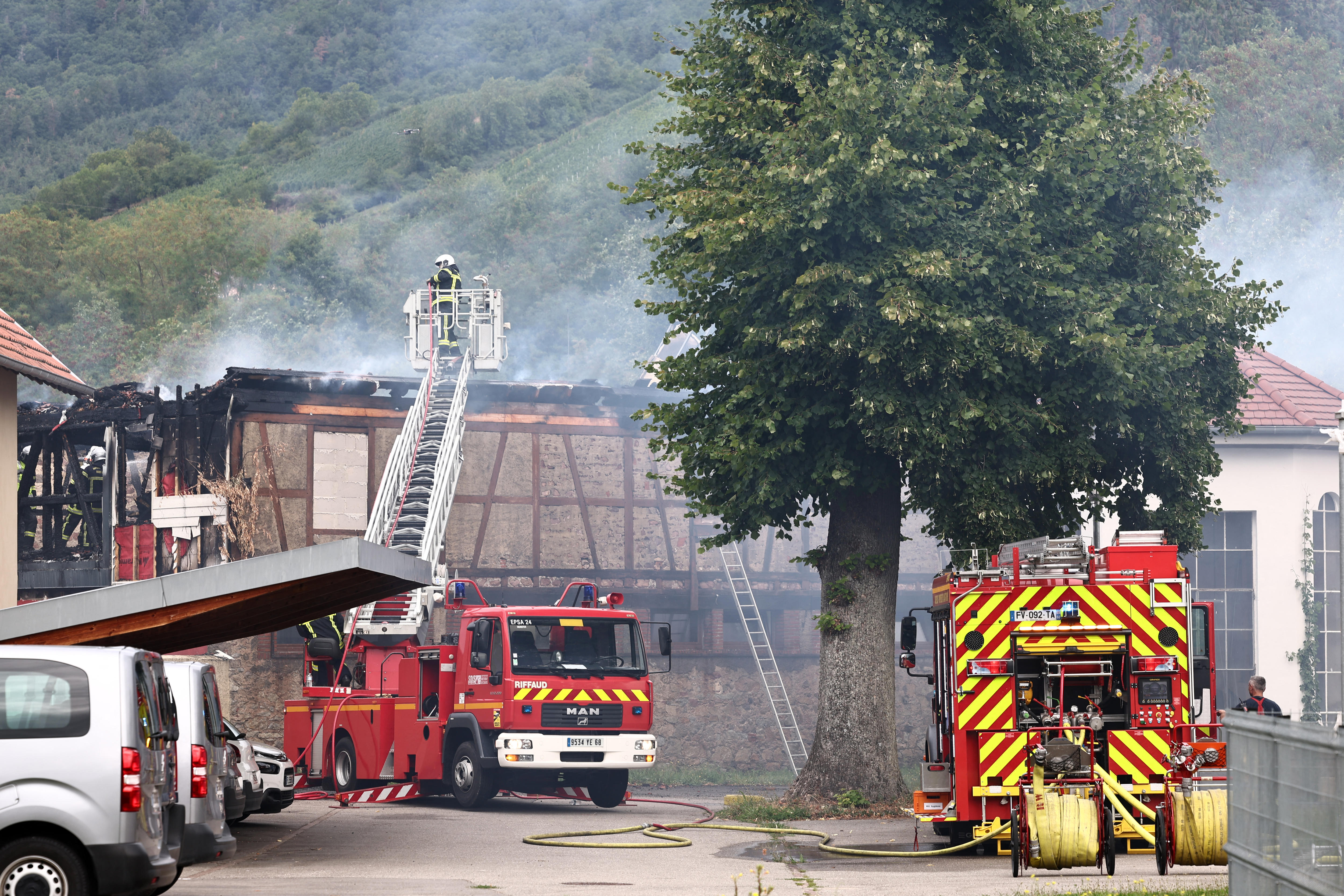 Fire trucks outside a building with smoke coming out of it. 