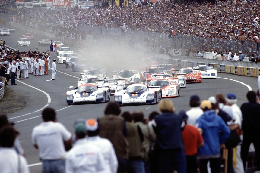The full field of the 1982 24 Hours of Le Mans start, driving up the hill, through the wet conditions.