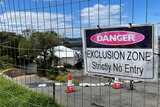 A warning sign hangs on a fence out the front of a landslip-damaged property.