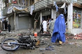 Afghan woman walks past site of suicide attack in Jalalabad, Afghanistan