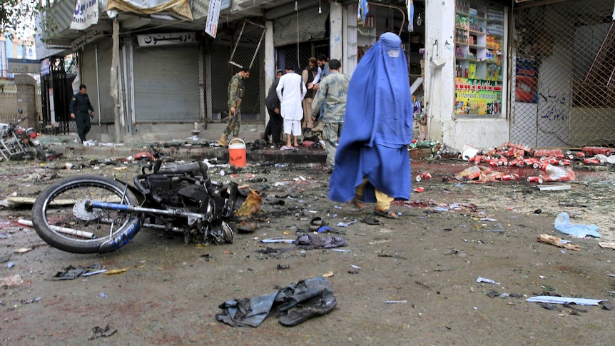 Afghan woman walks past site of suicide attack in Jalalabad, Afghanistan