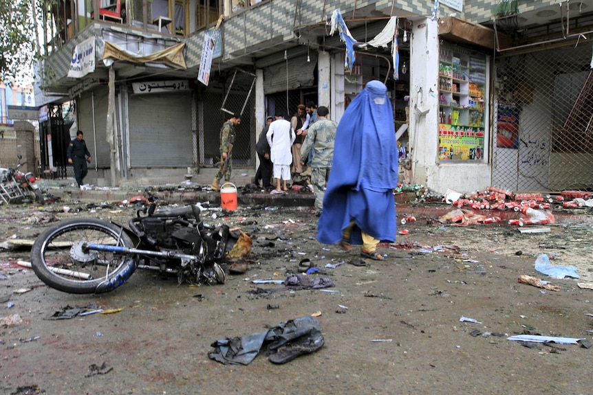 Afghan woman walks past site of suicide attack in Jalalabad, Afghanistan