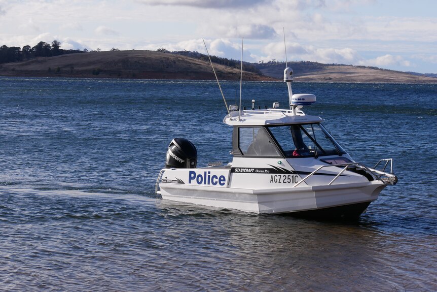 A police boat glides through the water of a lake