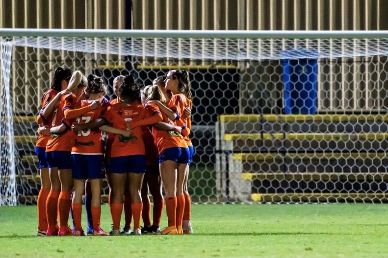 Women soccer players in a huddle.