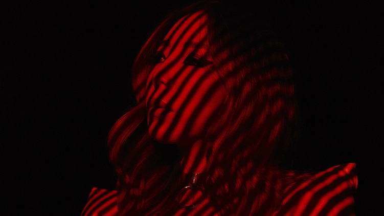 TOKiMONSTA in a suit with red and black lights streaming horizontally against her