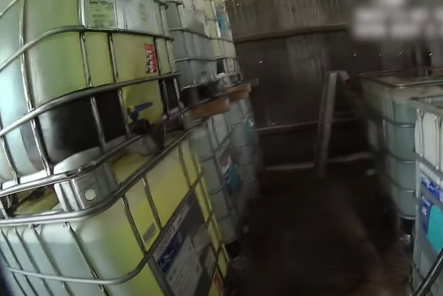 Vision from a body-worn camera showing large plastic pods of fuel in a shipping container.