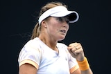 An Australian female professional tennis player pumps her left fist as she celebrates a win.