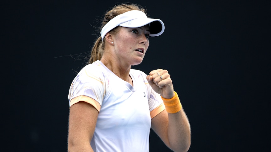 An Australian female professional tennis player pumps her left fist as she celebrates a win.