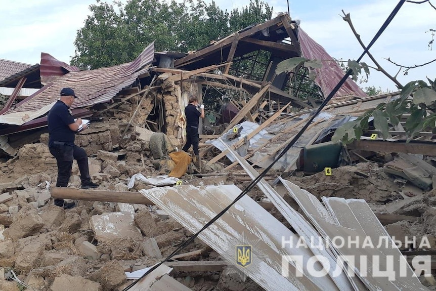 Officers inspect remains of a house destroyed by air strikes.