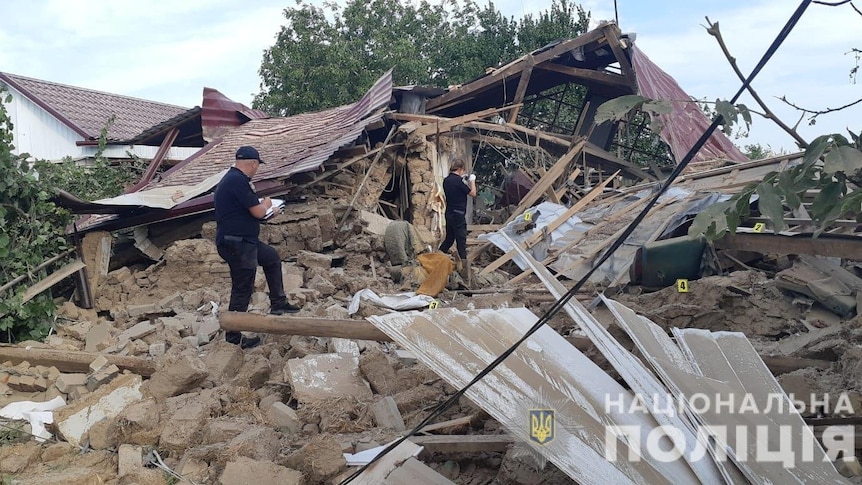 Officers inspect remains of a house destroyed by air strikes.