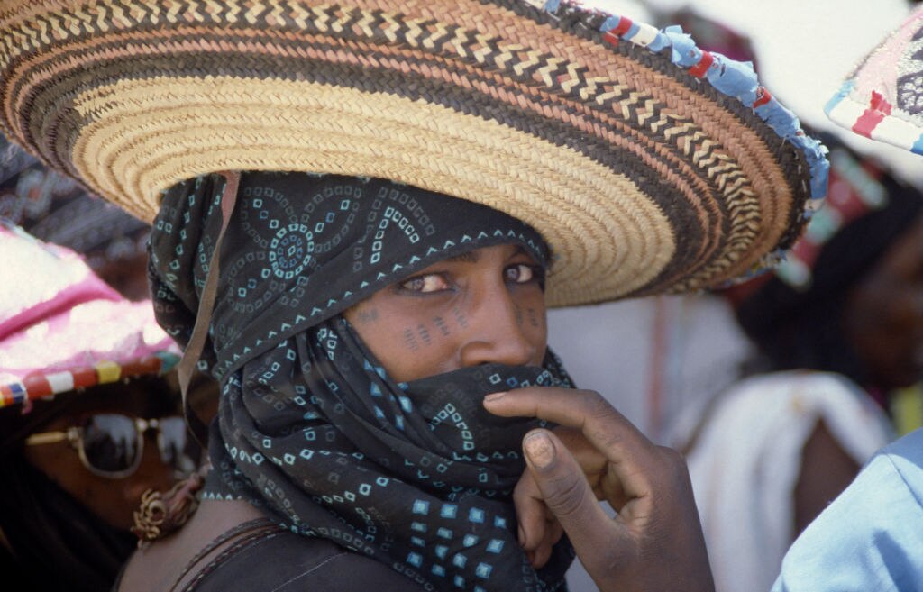 Portrait of Wodaabe man in Nigeria wearing wide brimmed hat and scarf
