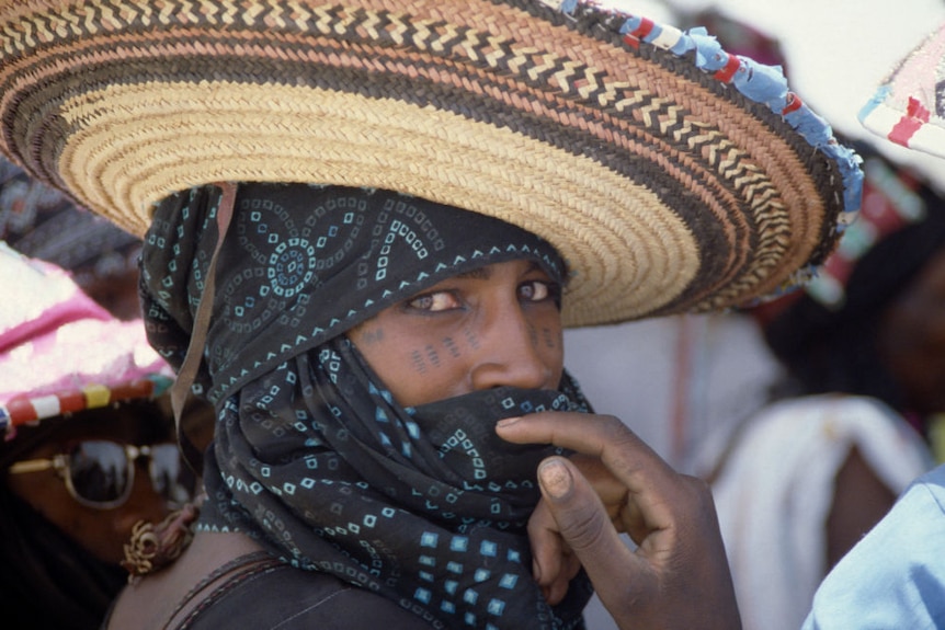 Portrait of Wodaabe man in Nigeria wearing wide brimmed hat and scarf