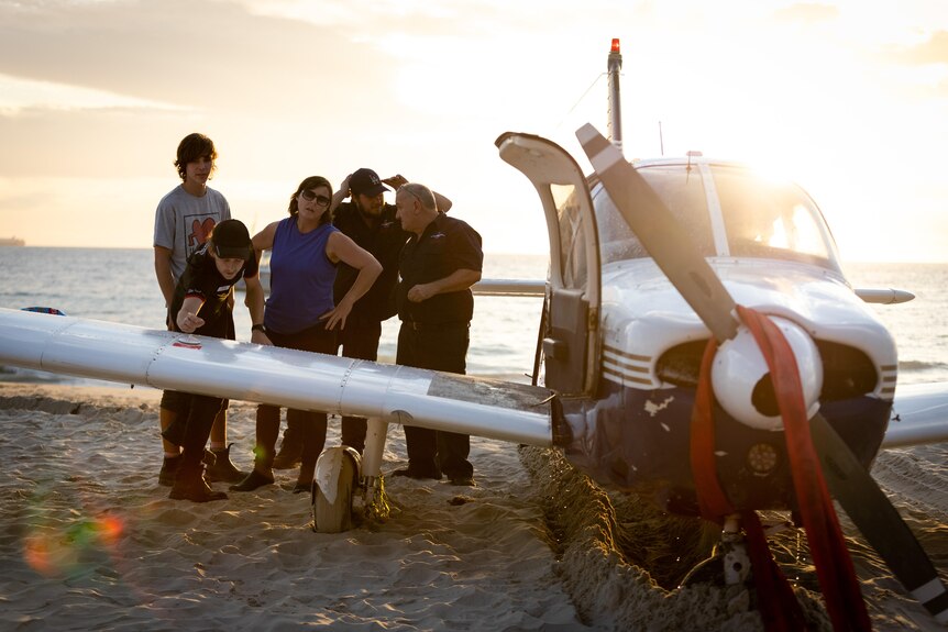 People inspecting a plane on the beach