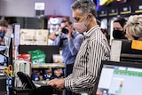 A man wearing a mask scans his ID inside a liquor store. 