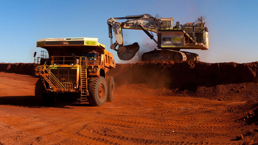 An earth mover shifts dirt into a truck