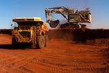 An earth mover shifts dirt into a truck in the Pilbara