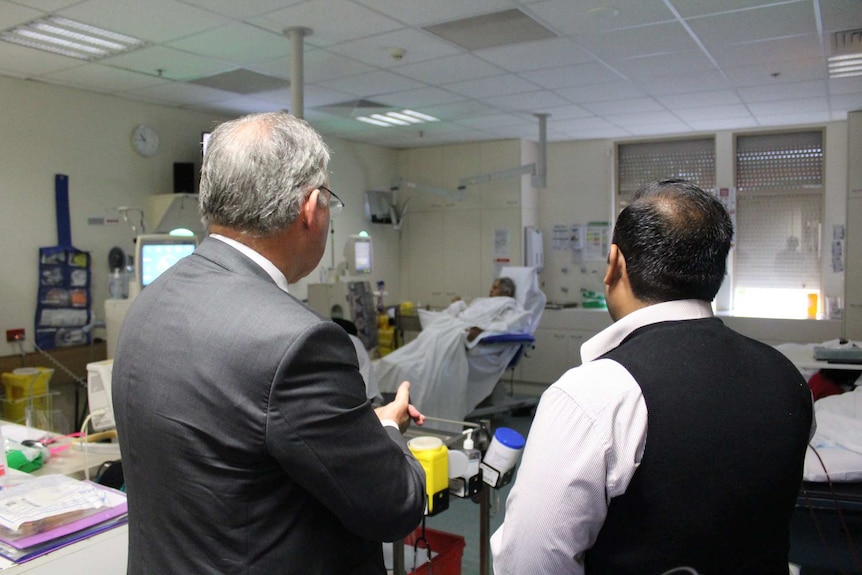 Two men stand looking at a haemodialysis ward