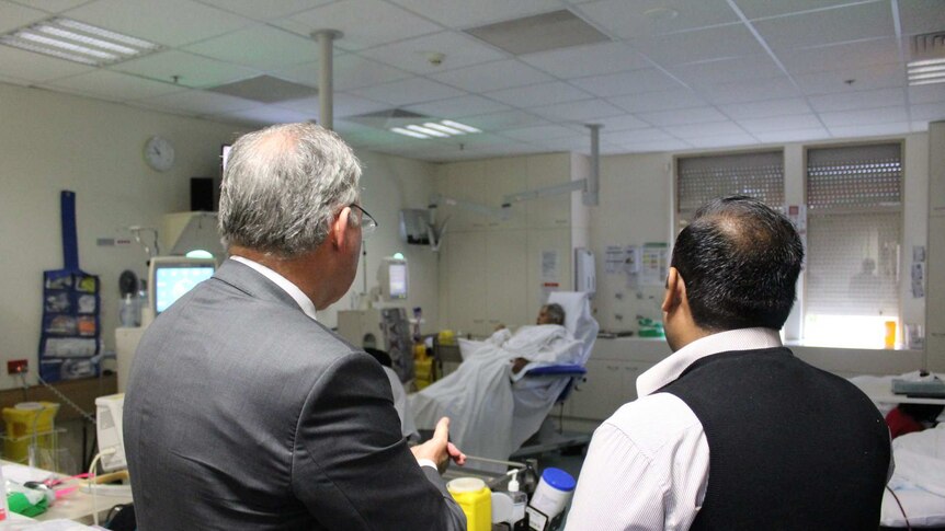 Two men stand looking at a haemodialysis ward