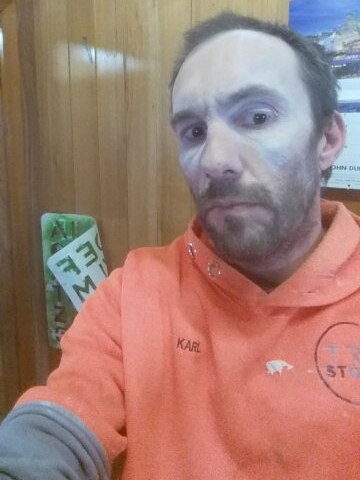 Man wearing hi-vis orange shirt with silica dust on his cheeks and forehead.