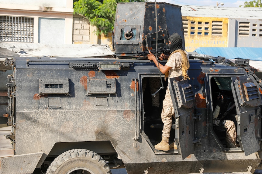 Policeman takes cover in an armored vehicle during an anti-gang operation.