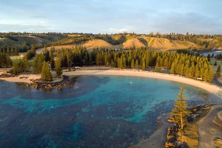 Aerial photo of Norfolk Island showcasing bright blue swimming bay called Emily Bay.