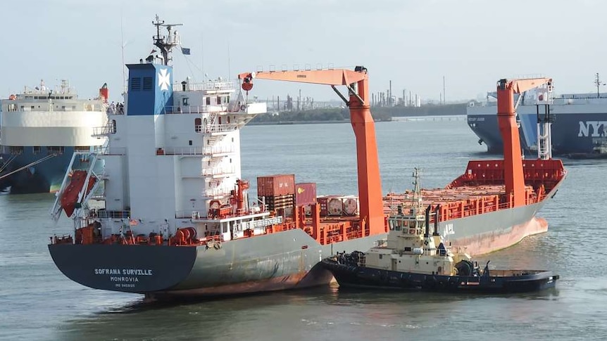 A cargo ship at port with city buildings in the background