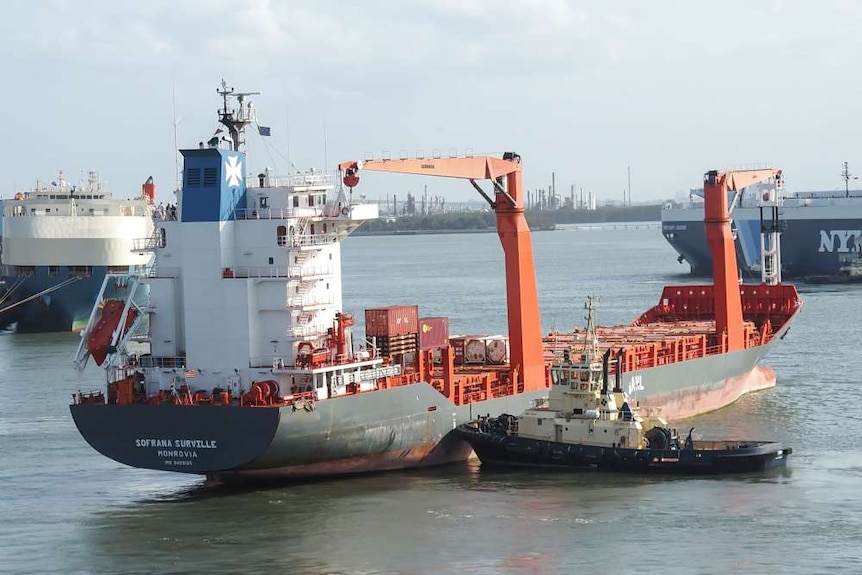 A cargo ship at port with city buildings in the background