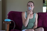 A photo of cystic fibrosis sufferer Justine Clason sitting on her couch using a nebuliser.