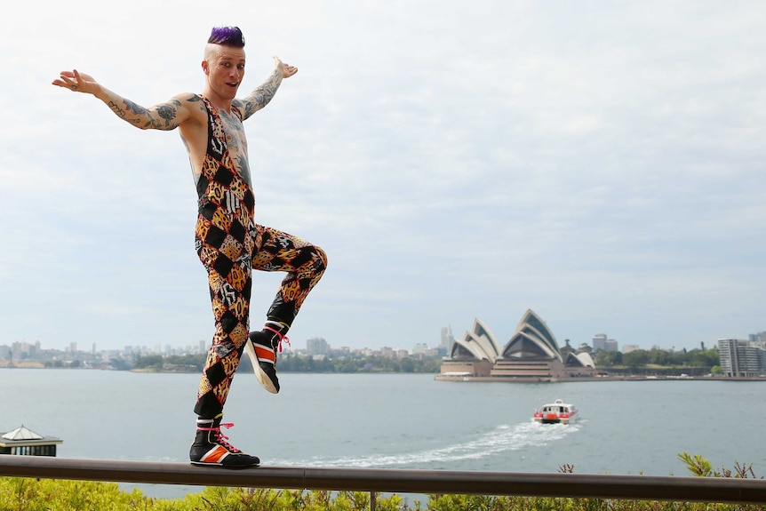 A circus performer balances on rail overlooking Sydney Harbour.