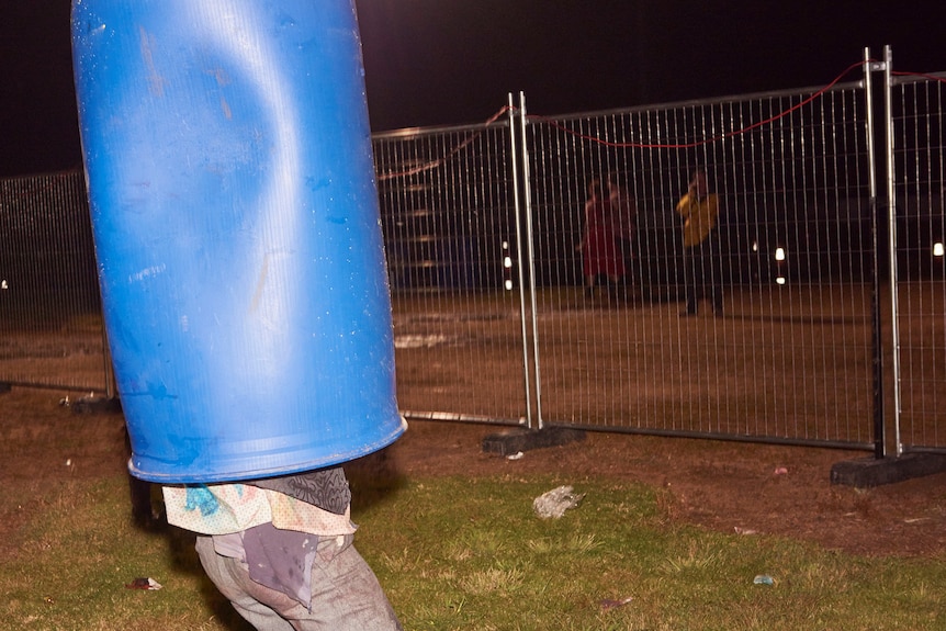 Man standing with a blue bin over his head