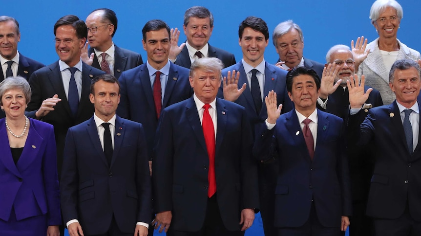 G20 world leaders leaders stand together as they pose for a group photo.