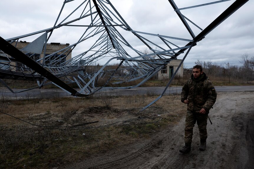 A Ukrainian soldier walks under a communications tower that fell from a strike.