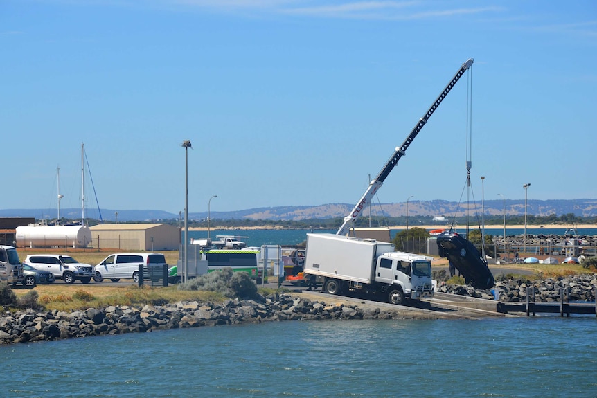 A car hangs from a tall crane after being pulled from the water at Bunbury port.