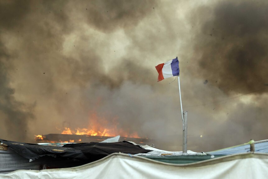 Shelters have been set on fire by migrants as they are forced to evacuate the camp.