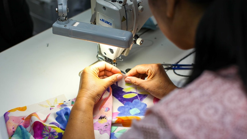 A woman sewing a piece of fabric.