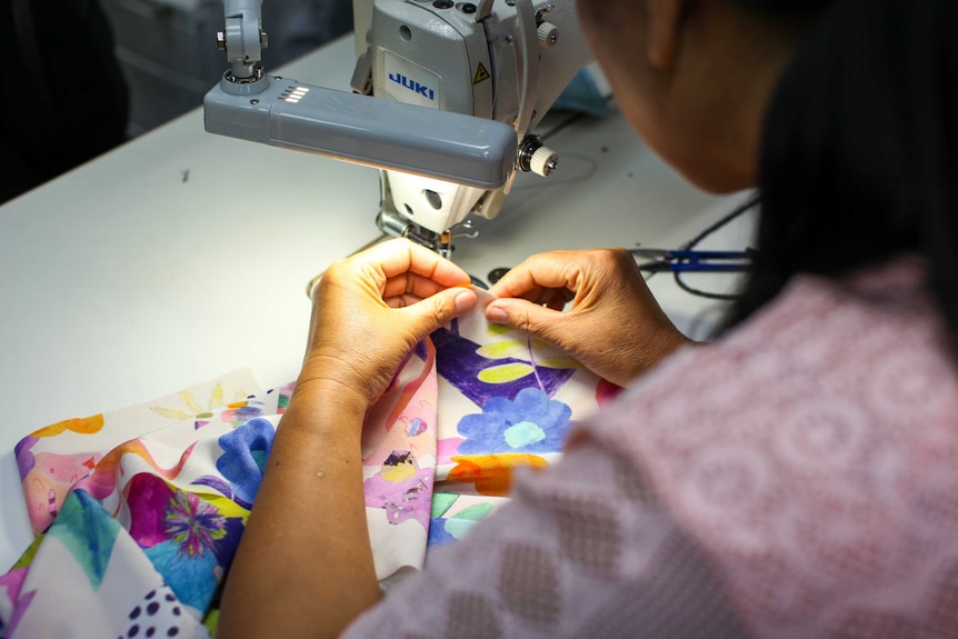 A woman sewing a piece of fabric.