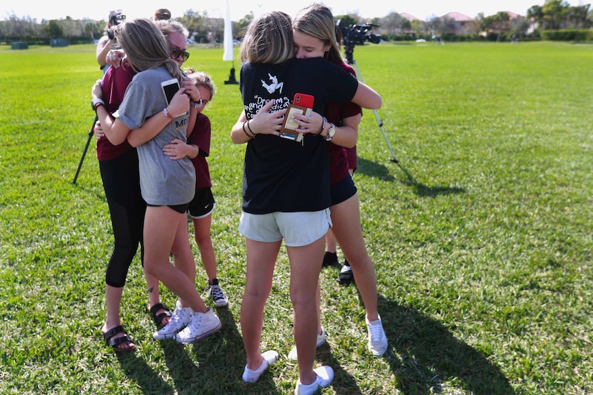 People embrace at the memorial outside Marjory Stoneman Douglas High School